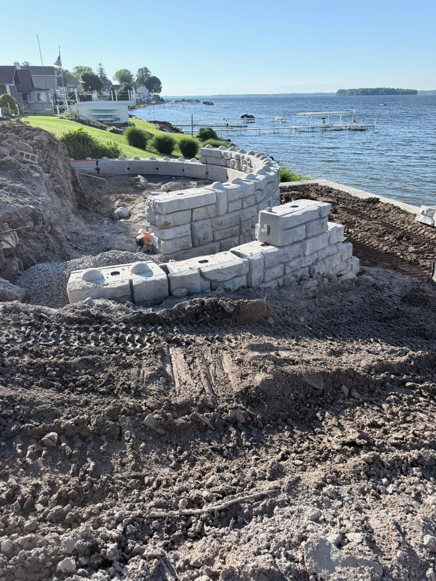 Curved precast concrete block retaining wall being built along a lakeshore