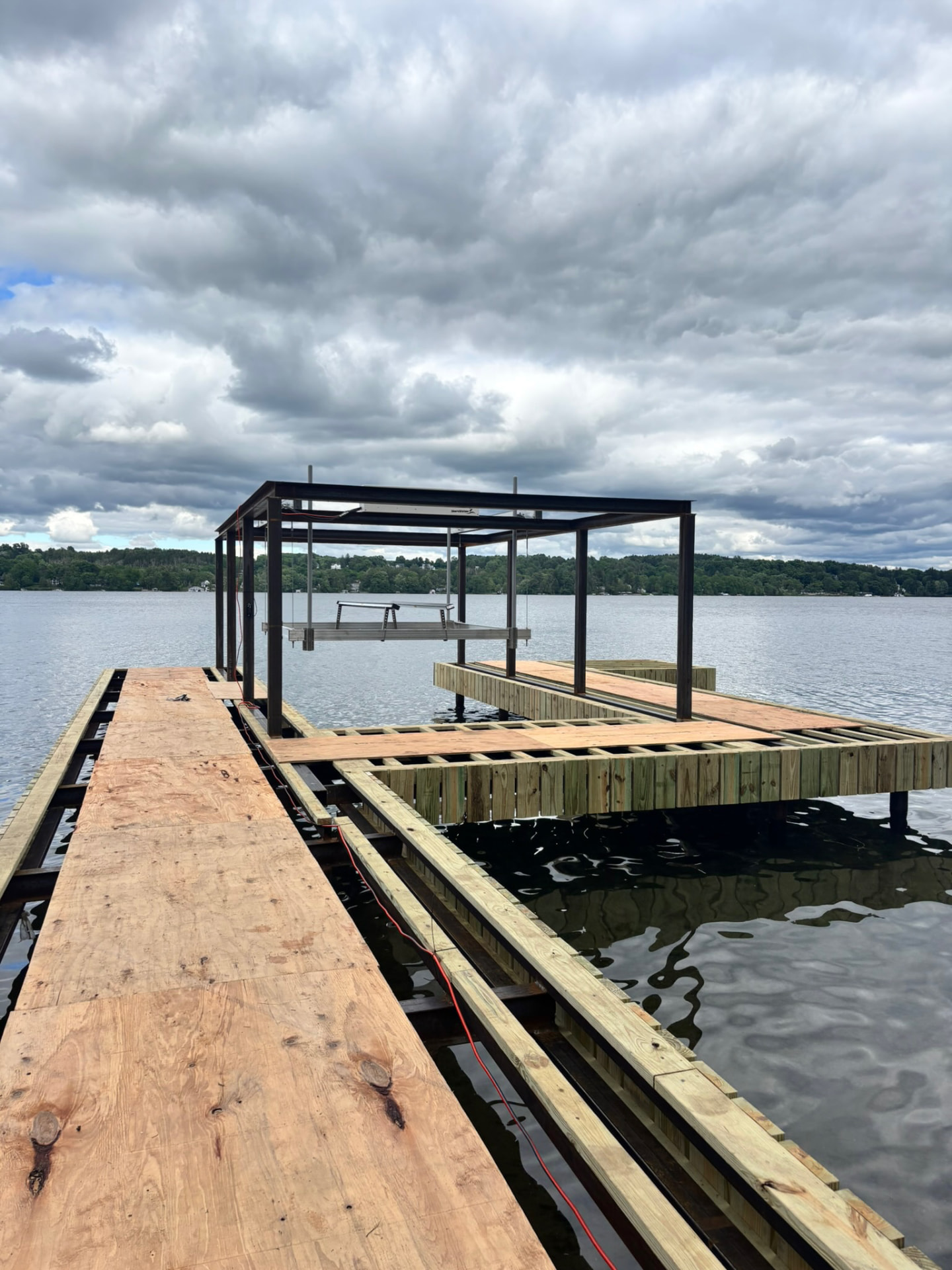 Steel-framed dock and boat lift under construction on a calm lake