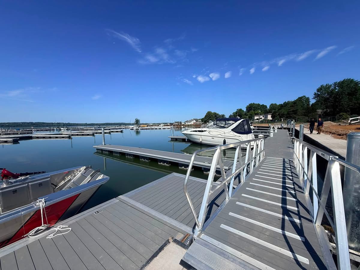 Marina dock system with aluminum gangway and boats moored under a clear blue sky