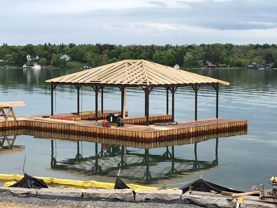 Timber-frame boat house roof under construction over a new lakefront dock