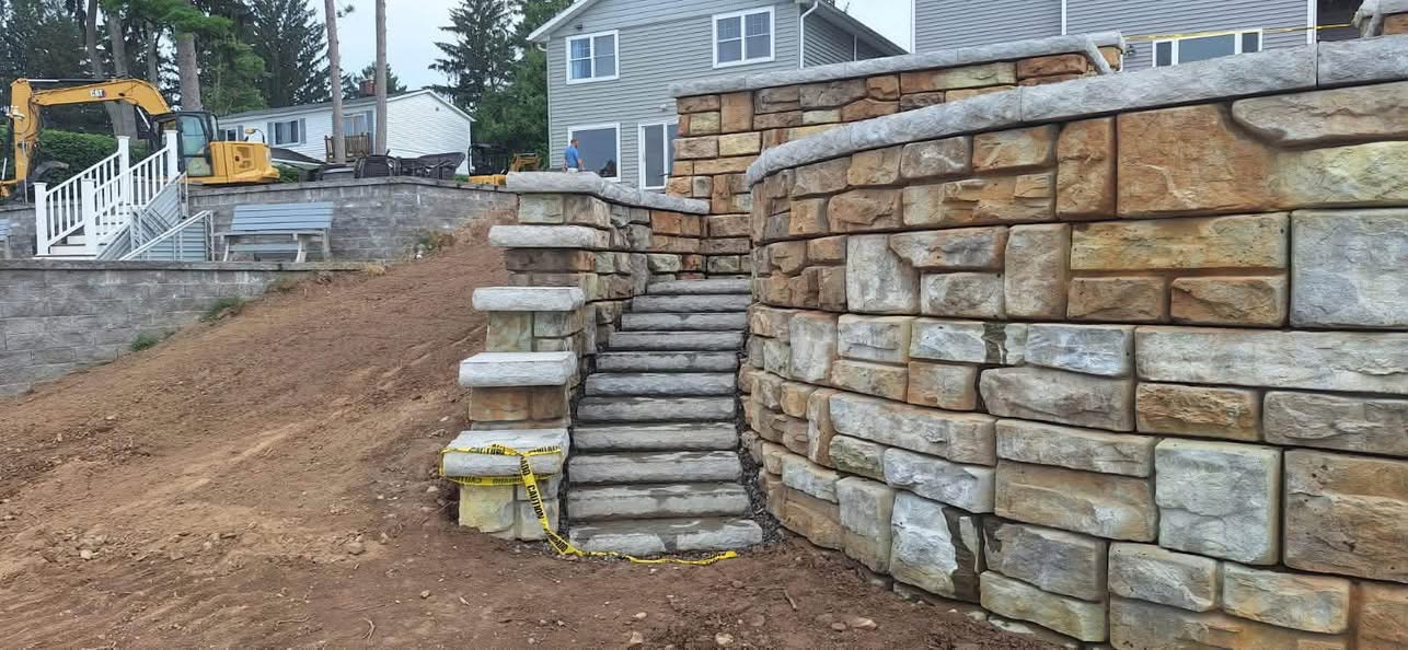 Large block retaining wall with stone stairway and regraded slope