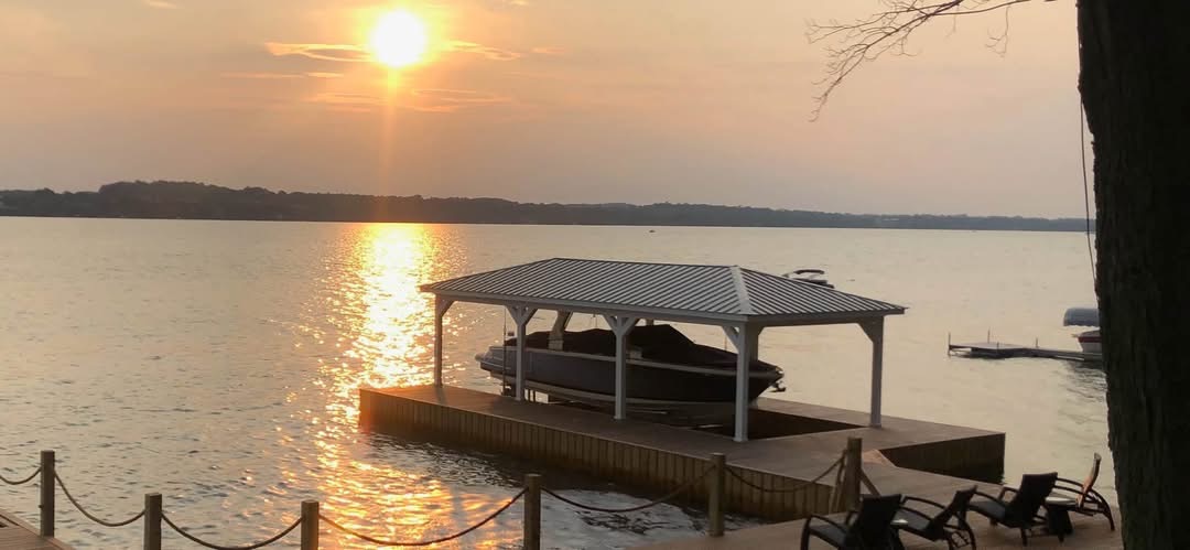 Covered boat lift and dock at sunset on a calm lake